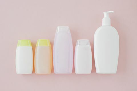 Sticlele neetichetate de produse cosmetice pe un fundal roz