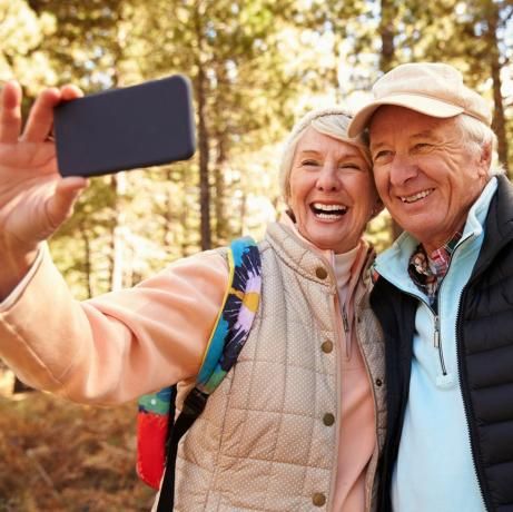 Cuplu în vârstă într-o plimbare într-o pădure făcându-se un selfie