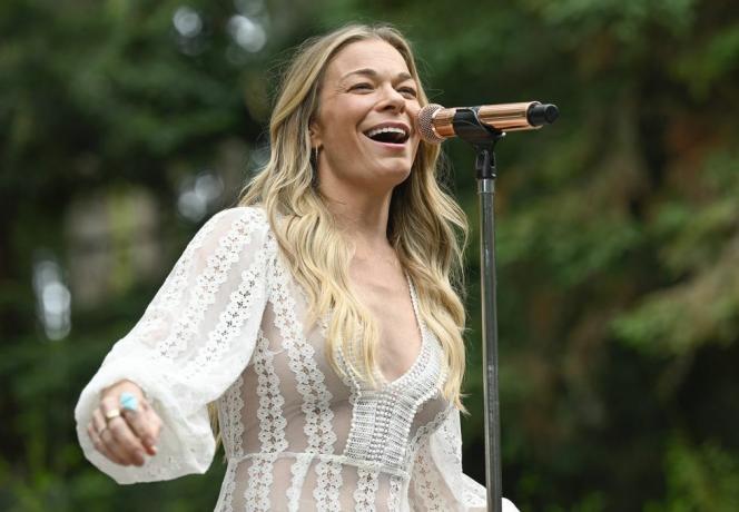 Leann Rimes cântă pe scenă cu microfon în rochie albă din dantelă