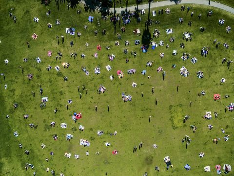 Vedere deasupra oamenilor într-un parc din oraș într-o zi de vară, stând, în picioare, pe covoare de picnic.