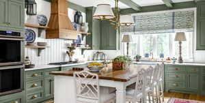 bucătărie cu dulapuri vopsite în verde liniștitor, căpriori și ornamente combinate cu pereți, tavan și insulă cu panouri albe
