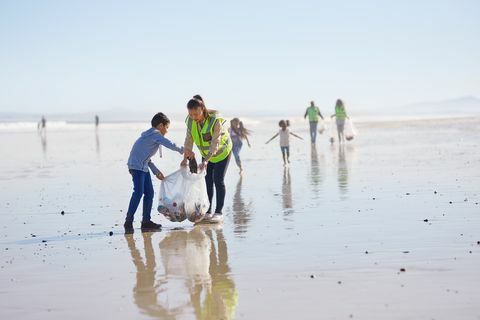 Mama și fiul fac voluntarii de curățare a gunoiului pe plaja cu nisip umed