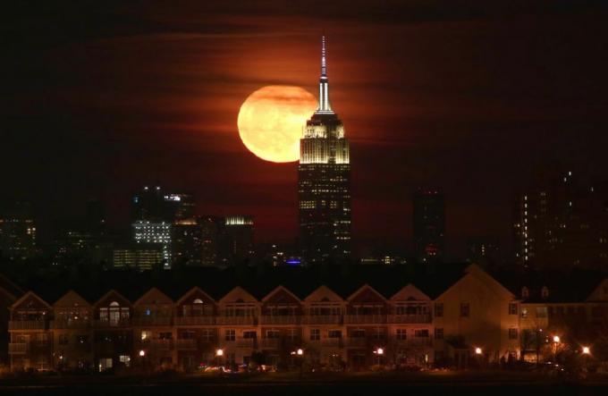 Luna plină se ridică în spatele clădirii Empire State din New York