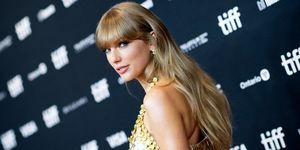 Taylor Swift privind peste umăr pe covorul roșu în rochie aurie