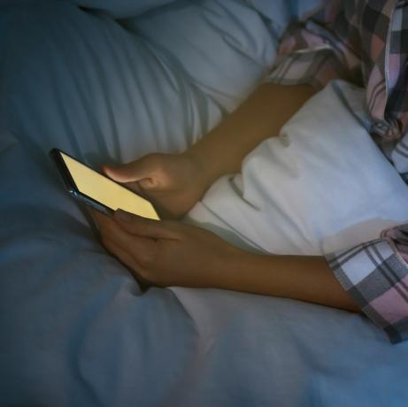 femeie care folosește un smartphone în pat noaptea, nomofobie în prim plan și problemă de tulburare de somn