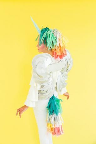 femeie îmbrăcată ca parte pegas, parte unicorn cu coadă și coamă de hârtie multicoloră, aripi albe și corn alb
