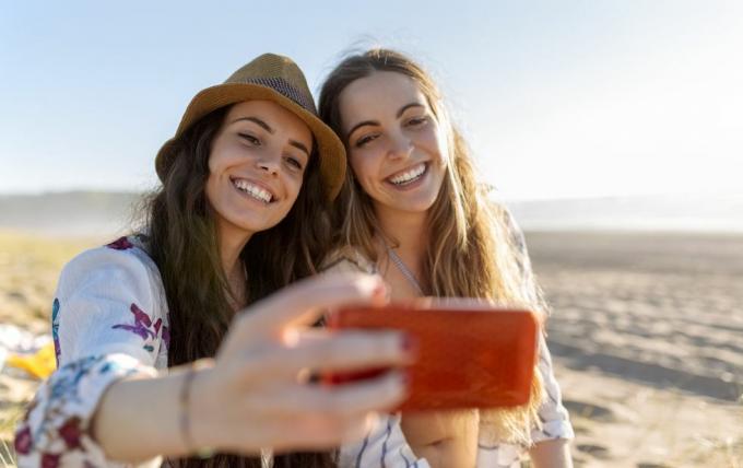 doi cei mai buni prieteni făcând selfie cu smartphone-ul pe plajă