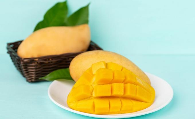 Prim-plan cu fructe de mango în farfurie peste fundal albastru