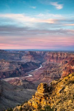 vedere pitorească a parcului național Grand Canyon cu apus de soare în fundal și râu care curge prin el