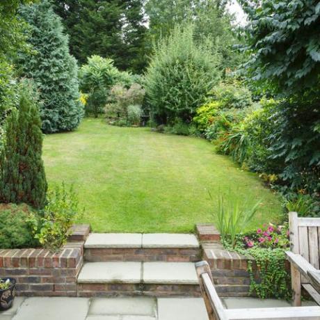 Grădină din spate terasată și amenajată în Anglia Marea Britanie, cu terasă, iarbă și trepte de piatră