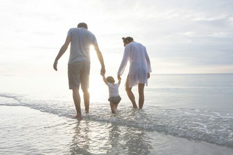 o familie mână-în-mână care merge pe plajă