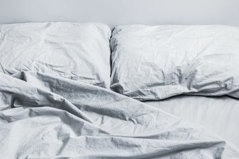 lenjerie de pat gri dezordonat pat cu doua perne la lumina zilei