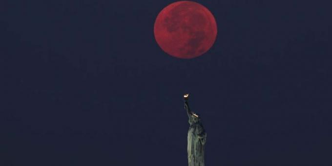 Luna plină apune în spatele statuii libertății din orașul New York