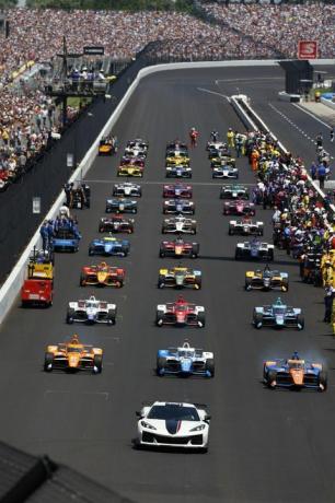 Indianapolis 500 cu vedere frontală a mașinilor pe pista de curse aliniate și a oamenilor în tribune