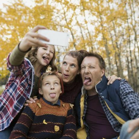 Familie prostească făcând selfie-uri făcând fețe în parc de toamnă