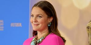 Drew Barrymore purtând o rochie roz cu pelerină și bijuterii turcoaz la covorul roșu al premiului Emmy în timpul zilei