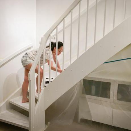 femeie aplicând vopsea albă proaspătă pe scări