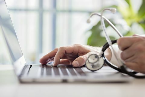 Medicul care introduce notele pacientului pe laptop în operație